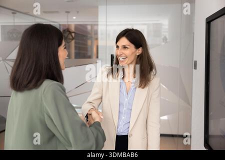 Two professional women shaking hands in modern office Stock Photo