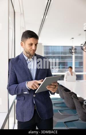 Young businessman in suit working on digital tablet device Stock Photo