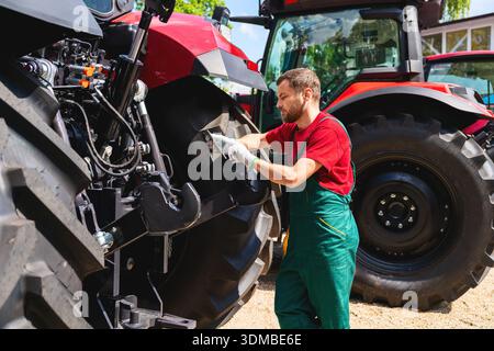 Mechanic using tablet to inspect tractor outdoors Stock Photo