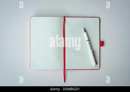 Open lined notebook with red bookmark and pen. Isolated on white surface, top view. Copy space. Stock Photo
