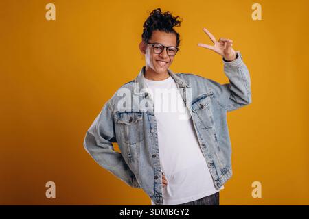 In jean jacket. Young guy is against yellow background. Stock Photo