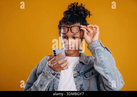 Internet conception, using smartphone. Young guy is against yellow background. Stock Photo