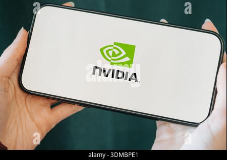 Close-up of a smartphone held in hands displaying the NVIDIA logo on the screen. Concept of modern technology, artificial intelligence, GPU computing, Stock Photo