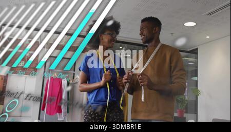 Standing two designers discussing garment fit in modern studio, with measuring tapes and pink top Stock Photo
