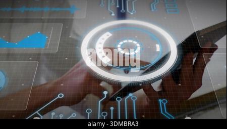 Tapping touchscreen, adult male hands navigating HUD, blue charts, waves and circuit traces at desk Stock Photo