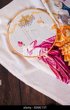 Handmade embroidery with colorful thread on fabric. Scissors, needle, and a pin cushion are placed nearby, emphasizing the craft and needlework proces Stock Photo