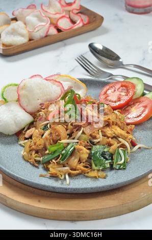 Fried flat rice noodles Char Kway Teow with egg, and vegetables on a white plate, Indonesian dish. Stock Photo