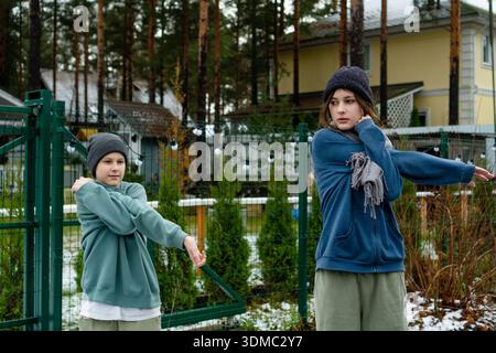 A brother and sister stretch shoulder and forearm muscles as part of a pre-run warm-up routine. This image highlights the importance of muscle preparation, flexibility Stock Photo