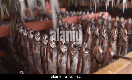 Numerous rows of fish hanging on racks for smoking and drying. Industrial food production at a seafood processing and preservation factory Stock Photo