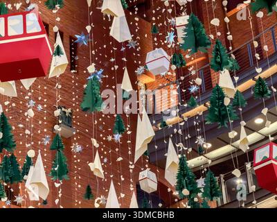 Low angle view of intricate paper decoration showcasing green Christmas trees, sparkling stars, ski gondolas, against a brick wall, creating a magical Stock Photo