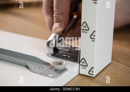 Close-up of a person's hand diligently using a ratchet screwdriver to fasten a screw, efficiently building new home furniture for interior design Stock Photo