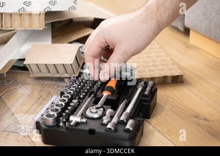 Close-up of a person's hand choosing a specific screwdriver bit from a comprehensive metal tool set, emphasizing essential equipment for various maint Stock Photo