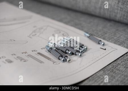 Close-up of new furniture connectors and fasteners laid on a printed assembly guide, highlighting the initial stage of a DIY home furnishing task or o Stock Photo