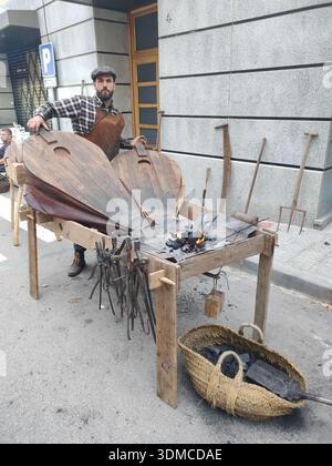 Detail of an old blacksmith working on forging tools in the street, fair of the old craftsmen's guilds. Stock Photo