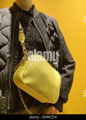 Detail of a yellow leather handbag displayed on a mannequin in the window of a modern fashion store Stock Photo