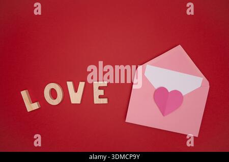 This image conveys a warm and heartfelt message of love and affection. Featuring wooden letters spelling "LOVE" alongside a delicate pink envelope and Stock Photo