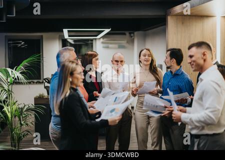 Diverse team meets in a modern office, discussing documents and charts for a collaborative project Stock Photo
