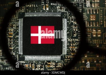 Flag of Denmark on a processor. Computer board with chip. View through magnifying glass Stock Photo