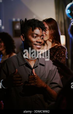 Young Black Man Smiling and Gesturing Thumbs up at Party with Friends Stock Photo