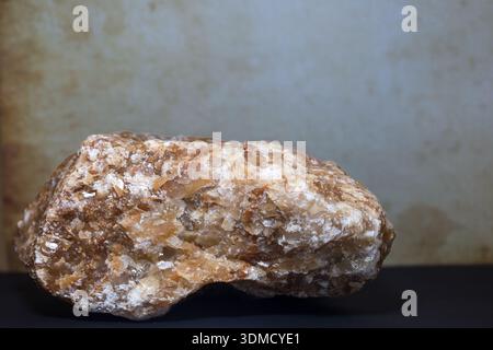 A large, raw honey calcite stone with a rich golden-brown tone and natural crystal texture. Stock Photo