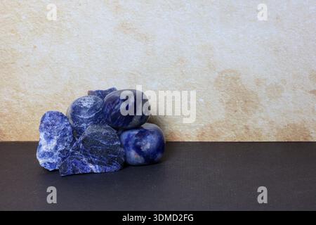 Group of Sodalite stones including natural raw specimens and polished tumbled crystals, placed on a clean neutral surface Stock Photo
