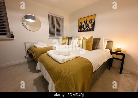 A bedroom with two beds and a mirror. The beds are covered in yellow blankets and pillows Stock Photo