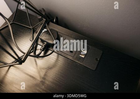 A black table with a black power strip on it. The power strip has two outlets and a USB port Stock Photo