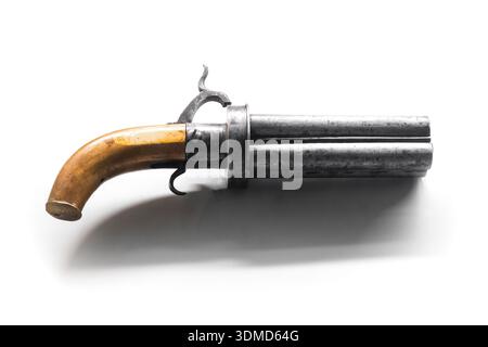 An antique revolver pistol with a wooden grip and four barrels sits against a bright white background. A historical firearm vibe, perfect for collecti Stock Photo