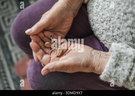 Senior woman holding hearing aid in her hands Stock Photo