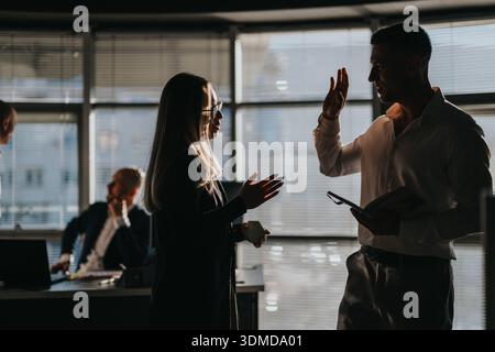 Two business people exchange a high five in a modern office during a discussion Stock Photo