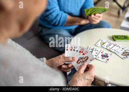 Elderly women playing cards in a nursing home, focus on the hands Stock Photo