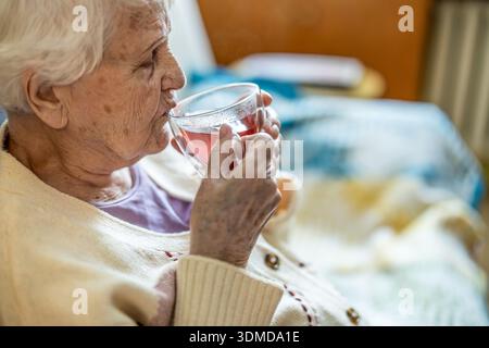 Elderly woman drinking a cup of tea in a nursing home Stock Photo