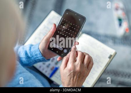 Senior woman using mobile phone at home, closeup of hands Stock Photo