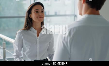 Two Caucasian business colleagues talking in company hall businesswoman talk serious with businessman in office corridor coworkers partners Stock Photo
