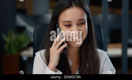 Happy Caucasian businesswoman talking phone call looking in laptop smiling business woman talk mobile conversation communicating smartphone with Stock Photo