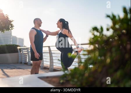A couple participates in a stretching session by the water, showcasing their commitment to fitness and health while cherishing their special moments t Stock Photo