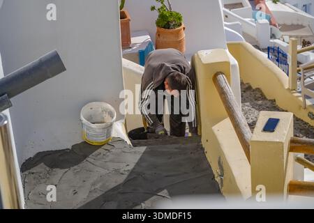 Construction worker / builder repairing a terrace floor with cement in Oia, Santorini. Renovation work on traditional Cycladic architecture. Stock Photo
