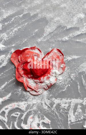 A red painted heart on red artificial leaves fixed with pins in the shape of a heart for DIY, hobby, handicrafts, Mother's Day Stock Photo