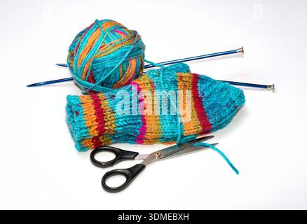 A pair of vibrant colored knit mittens with the ball of yarn they were made from and the tools used to make them. Stock Photo