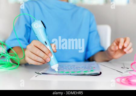 Child using a 3D printing pen for creative learning at a desk. Modern education concept with hands-on activity, bright colors, technology and imaginat Stock Photo