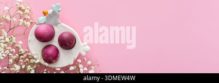 Spring Easter background, multi-colored Easter eggs in a decorative hen with gypsophila flowers on a pink background, copy space, banner Stock Photo