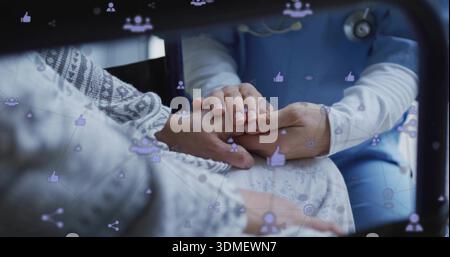 Holding caregiver's hands covering patient's hand in clinic, showing stethoscope, patterned sweater Stock Photo