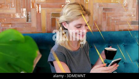 Smiling lady in grey dress checking phone at cafe holding black cup teal-bench plant-leaf wood-wall Stock Photo