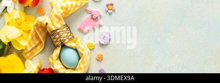 Bright spring flowers surround a beautifully set table with pastel Easter eggs, candy, and decorative elements, capturing the spirit of the holiday at Stock Photo