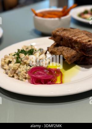 Grilled bread with creamy salad and pickled onions on a white plate, perfect for food background. Mobile photo Stock Photo