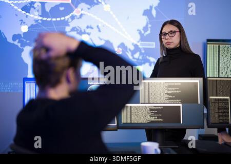 Cybersecurity professionals analyzing threat data on digital screens in control center Stock Photo