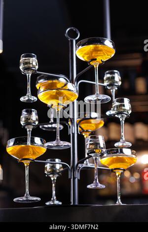 Multiple coupe glasses filled with cocktails arranged on display stand in bar. Ideal for hospitality, nightlife, and premium beverage marketing visual Stock Photo