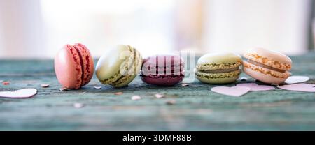 Colorful macarons arranged in a row on a old wooden table. Stock Photo