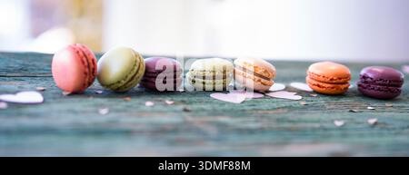 Colorful macarons arranged in a row on a old wooden table. Stock Photo