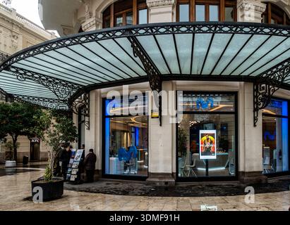 Modern Movistar telecommunications storefront with blue neon lighting under an ornate wrought iron canopy in the historic center of Valencia, Spain. Stock Photo